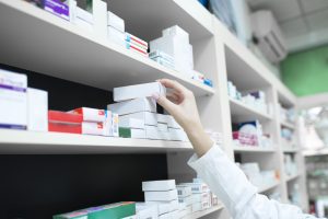 Closeup view of pharmacist hand taking medicine box from the shelf in drug store.