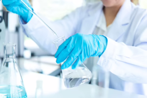 laboratorio7-laboratorio-pipeta-matraz-transparente-cientifica-guantes-azules-scaled